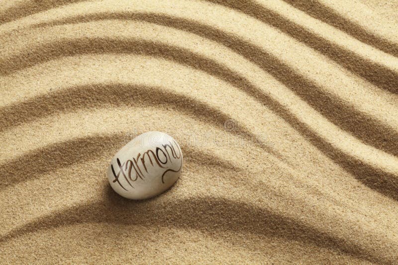 Harmony Pebble on sand. Harmony written on a pebble resting on a rippled sand zen garden background stock photos