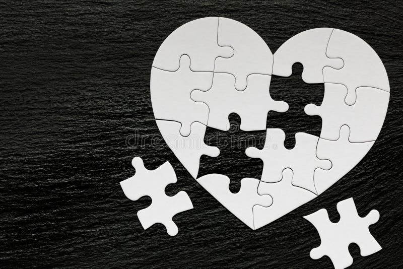 Hart-vormige puzzel in puzzel op achtergrond van kleur Puzzelhart op houten achtergrond Een vermist stuk van de hartpuzzel Hart