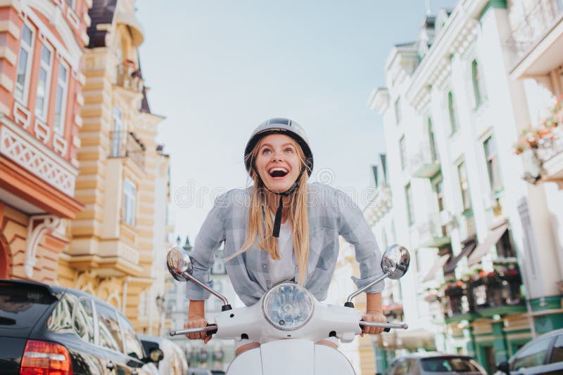 Persistent girl is trying to motorcycle start working. She is angry. She can`t ride. Girl wears helmet. She is in the middle of road. Persistent girl is trying to motorcycle start working. She is angry. She can`t ride. Girl wears helmet. She is in the middle of road