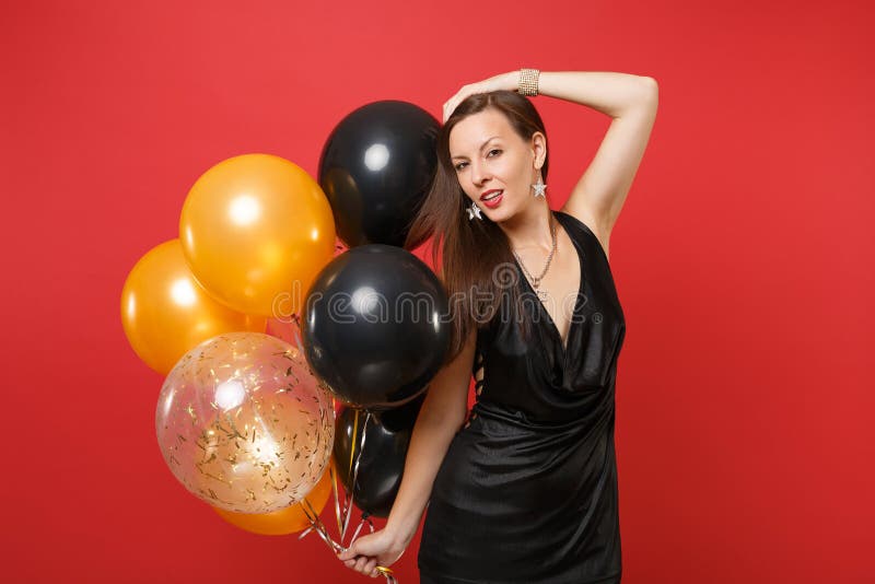 Hartstochts jong meisje dat in weinig zwarte kleding zettend hand op de hoofdballons viert van de greeplucht dat op rode achtergr royalty-vrije stock afbeelding Hartstochts jong meisje dat in weinig zwarte kleding zettend hand op de hoofdballons viert van de greeplucht dat op rode achtergr royalty-vrije stock afbeelding