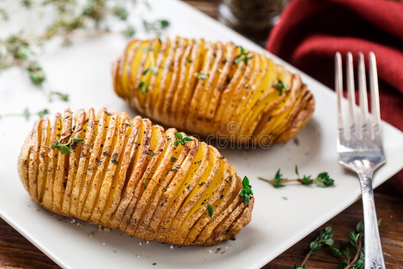 Hasselback potatoes with herbs on a plate. Hasselback potatoes with herbs on a plate