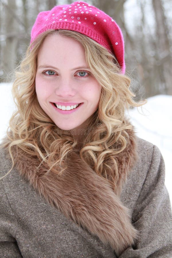 Portrait of a happy, smiling, wholesome, beautiful, green eyed young woman wearing a fur jacket and pink beret in a snowy forest. Portrait of a happy, smiling, wholesome, beautiful, green eyed young woman wearing a fur jacket and pink beret in a snowy forest.