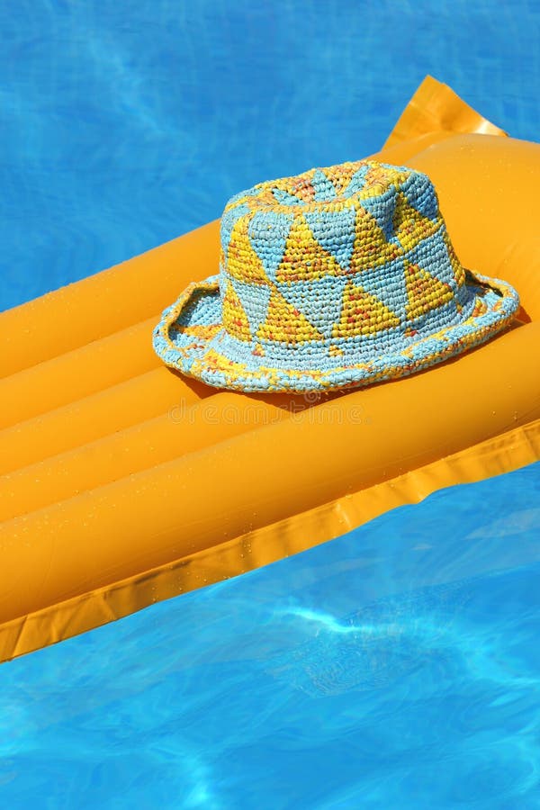 Cappello arancione materassino galleggiante in piscina.