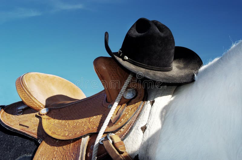 Vaquero un sombrero está descansando sobre el sillín durante.