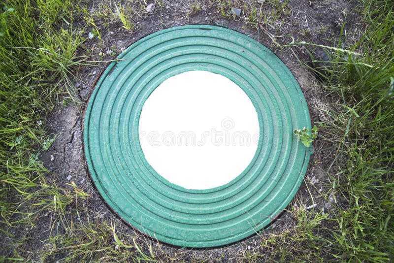 Hatch well cast iron heavy turquoise with a pattern of many rings on a background of green grass. In the center of the round white stock photography Hatch well cast iron heavy turquoise with a pattern of many rings on a background of green grass. In the center of the round white stock photography