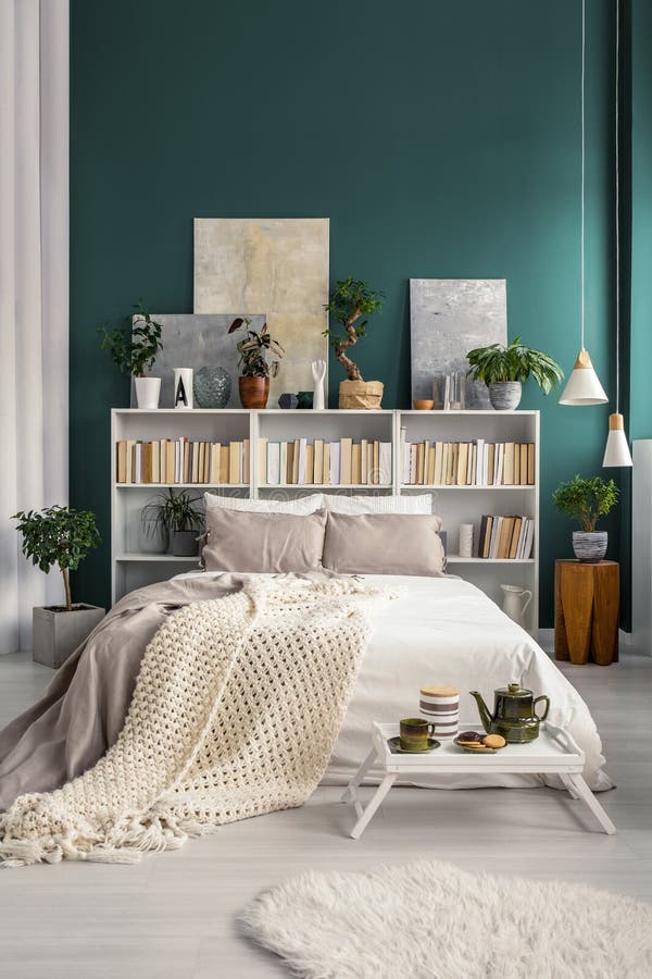 White home library with gray paintings and plants in a natural and spacious bedroom interior with turquoise green wall. White home library with gray paintings and plants in a natural and spacious bedroom interior with turquoise green wall