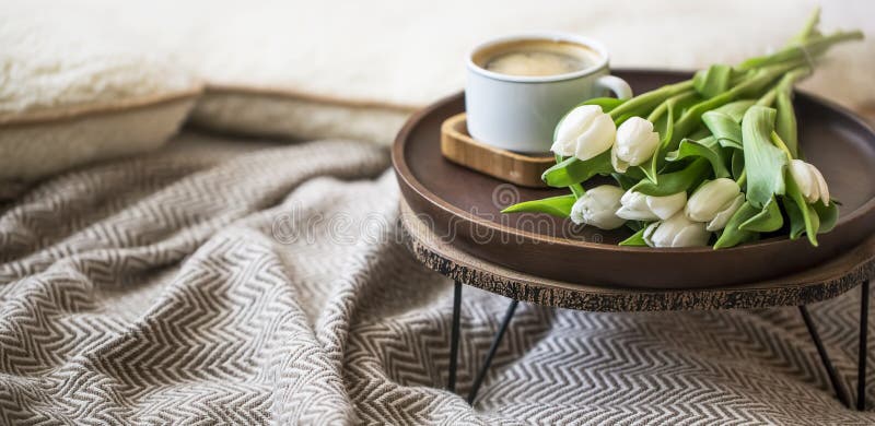 Hauptinnendekor mit Holztisch, Tulpenblumenblumenstrauß und Kaffeetasse, gemütliche Decke, Frühlingsinnenlebensstildekorationen