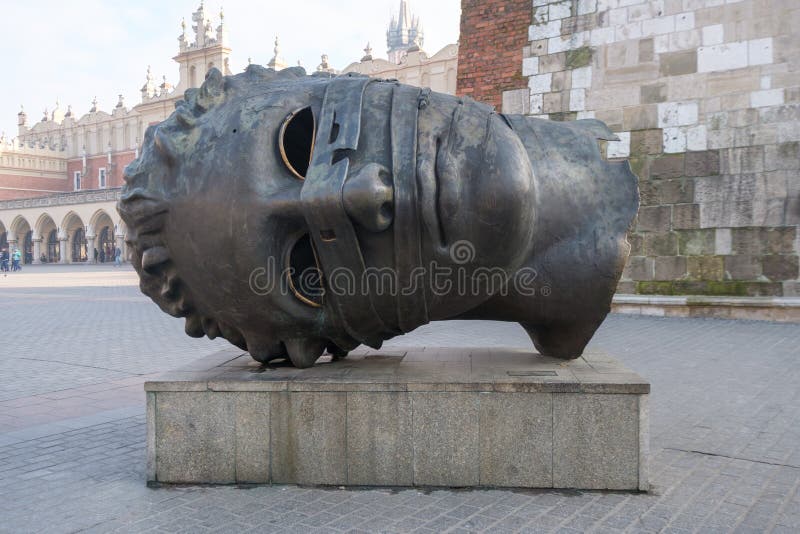 Krakow, Poland - December 20, 2016: Head sculpture Eros Bendato on Market Square by polish artist Igor Mitoraj. Krakow, Poland - December 20, 2016: Head sculpture Eros Bendato on Market Square by polish artist Igor Mitoraj