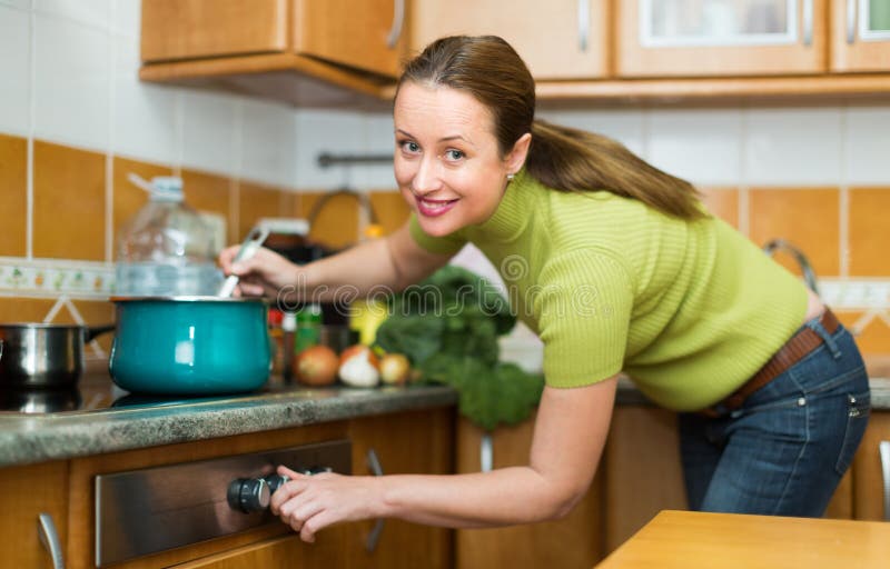 Hausfrau, die an der Küche kocht lizenzfreies stockbild Hausfrau, die an der Küche kocht lizenzfreies stockbild