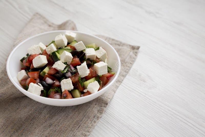 Hausgemachter Hirtensalat mit Gurken, Petersilie und Feta in einer weißen Schüssel auf weißer Holzoberfläche, seitlicher Blick Le lizenzfreie stockbilder Hausgemachter Hirtensalat mit Gurken, Petersilie und Feta in einer weißen Schüssel auf weißer Holzoberfläche, seitlicher Blick Le lizenzfreie stockbilder