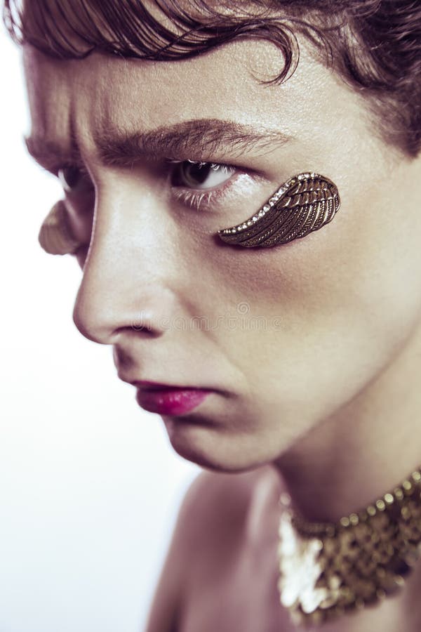 Hautecouture-Schönheit des jungen Modells mit Gold beflügelt piercing Schmuck und Make-up lizenzfreies stockfoto Hautecouture-Schönheit des jungen Modells mit Gold beflügelt piercing Schmuck und Make-up lizenzfreies stockfoto