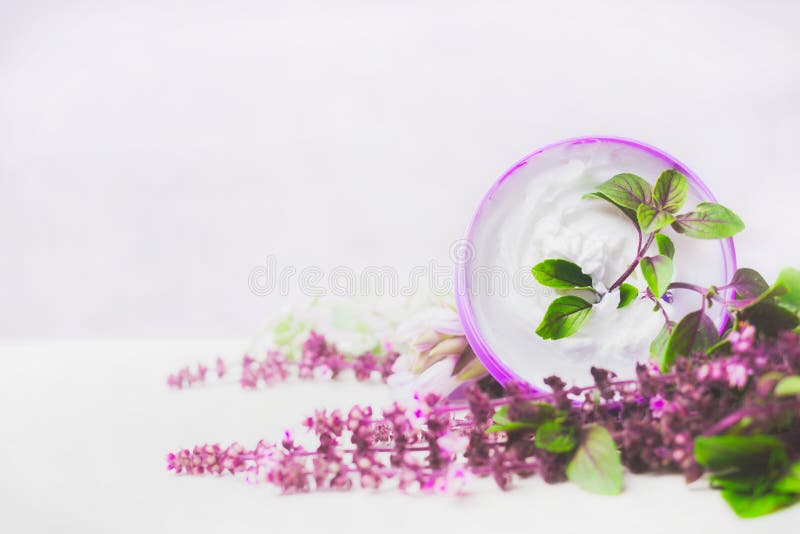 Hautpflegecreme im Glas mit purpurroten Kräutern auf weißem hölzernem Hintergrund Natürliche Kosmetik
