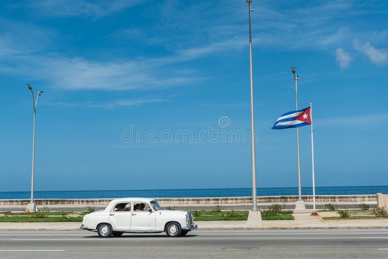 HAVANA, KUBA - 23. OKTOBER 2017: Havana Street mit wellenartig bewegender Flagge und altem Fahrzeug lizenzfreies stockbild HAVANA, KUBA - 23. OKTOBER 2017: Havana Street mit wellenartig bewegender Flagge und altem Fahrzeug lizenzfreies stockbild