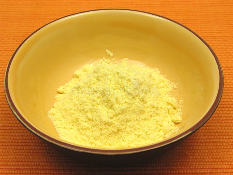 Cornmeal in a bowl of ceramic on an orange background. Cornmeal in a bowl of ceramic on an orange background
