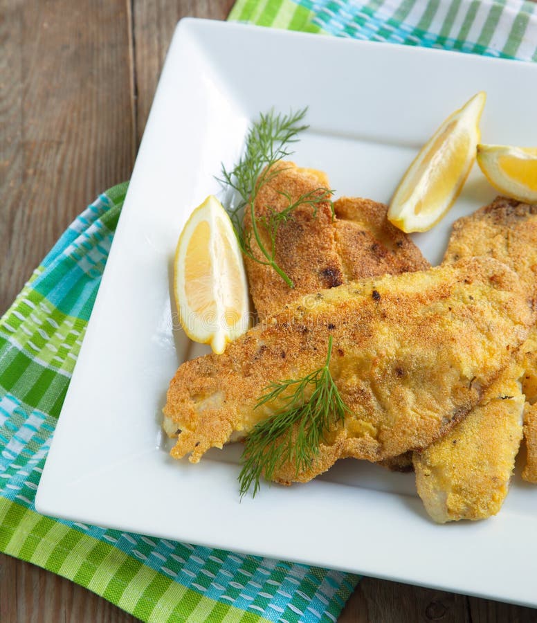 Cornmeal-crusted tilapia served in plate with lemon. Cornmeal-crusted tilapia served in plate with lemon