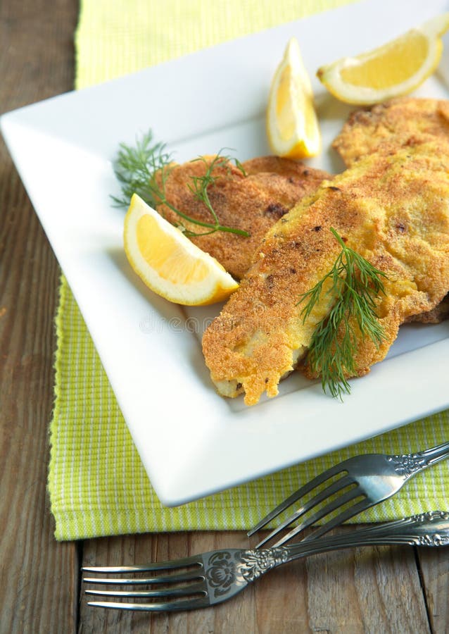 Cornmeal-crusted tilapia served in plate with lemon. Cornmeal-crusted tilapia served in plate with lemon