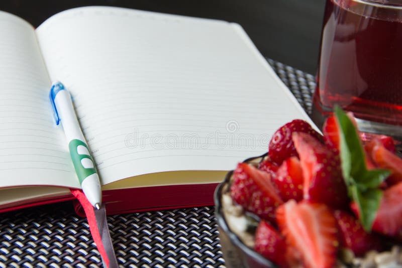 Porridge with strawberries and open notebook to plan daily business during breakfast. Porridge with strawberries and open notebook to plan daily business during breakfast