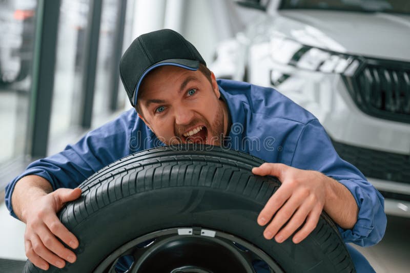 Having Fun, Smiling, with Tire. Man in Blue Uniform is Working in the
