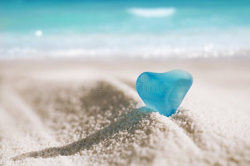 Havsglasblått hjärta på vit sandstrand