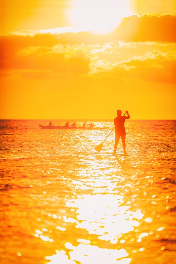 Hawaii ocean lifestyle - watersport activity on ocean - stand up paddleboard, people training on outrigger canoe