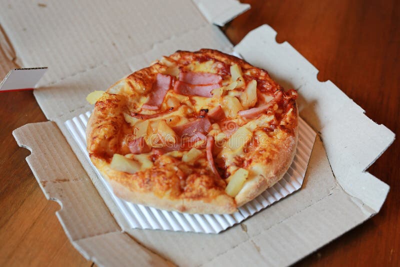 Hawaiian pizza in paper tray on wooden table stock photography Hawaiian pizza in paper tray on wooden table stock photography