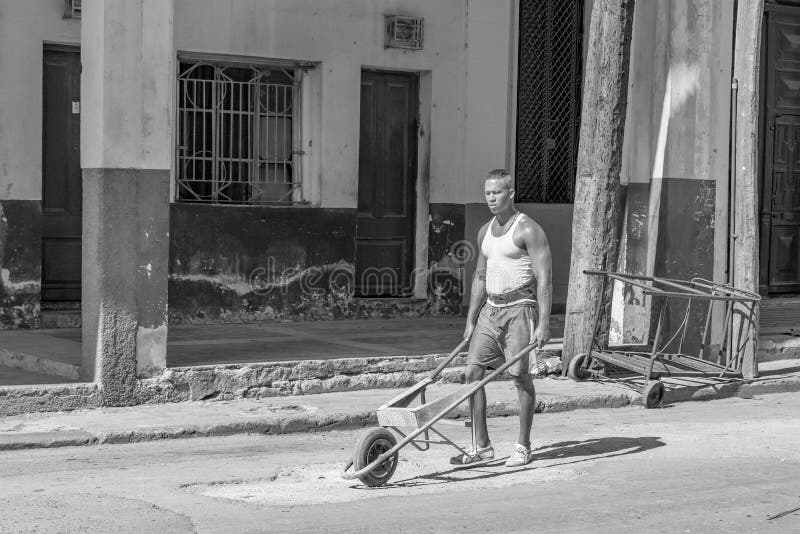 HAWAŃSKI, CUBA-OCTOBER 29 - mężczyzna stacza się staromodny koła taczkowego dla budowy pracy w ulicach Hawański, Oct 29, 2015 fotografia stock HAWAŃSKI, CUBA-OCTOBER 29 - mężczyzna stacza się staromodny koła taczkowego dla budowy pracy w ulicach Hawański, Oct 29, 2015 fotografia stock