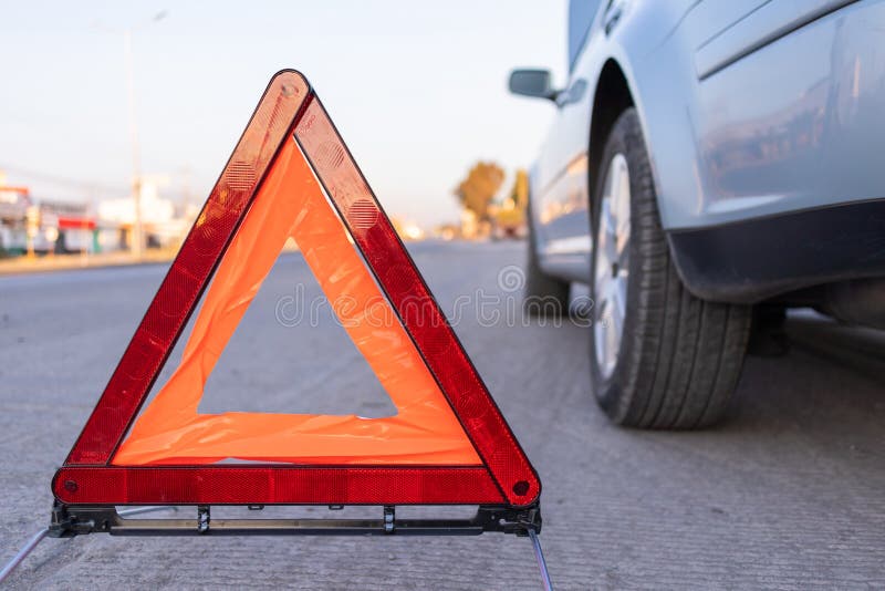 hazard triangle at the side of a grey car, emergency reflective hazard triangle on the road