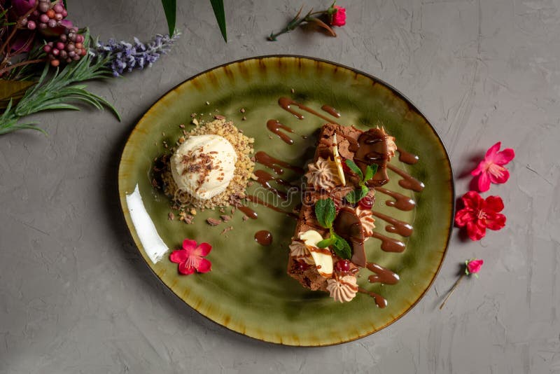 Hazelnootbrownie met chocoladebloemblaadjes en roomijs op een groene plaat stock afbeelding Hazelnootbrownie met chocoladebloemblaadjes en roomijs op een groene plaat stock afbeelding