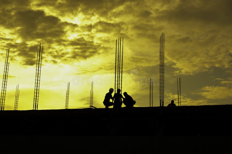 HDR effect of silhouette workers working at building construction side at sunset time royalty free stock photography