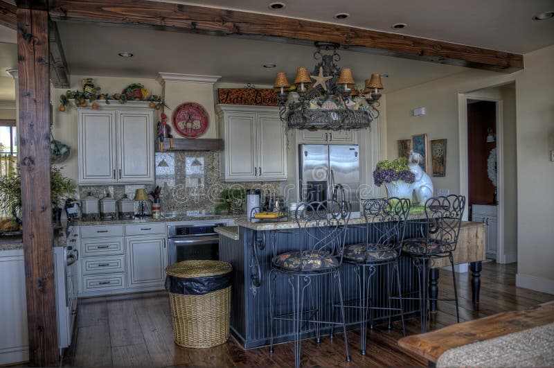This is an HDR image of a kitchen with a island eating area with a inch chandelier light. This is an HDR image of a kitchen with a island eating area with a inch chandelier light