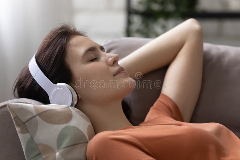 Peaceful young woman listening music or positive affirmations in headphones.