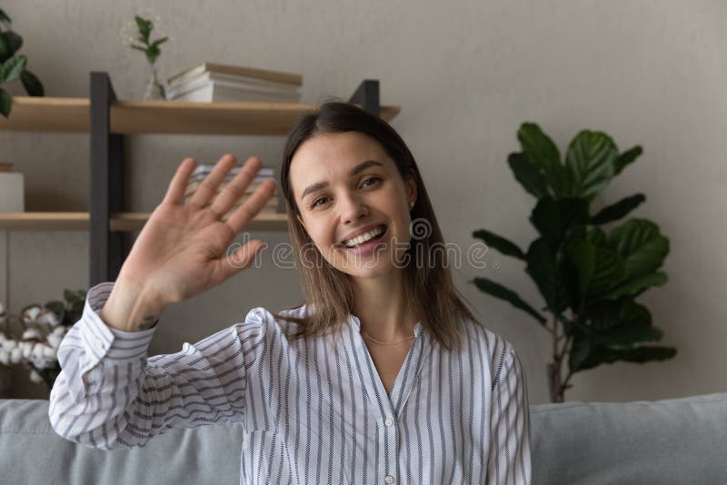 Head shot portrait smiling woman waving hand at camera