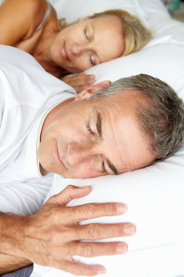Portrait head and shoulders shot of mid age couple sleeping in bed. Portrait head and shoulders shot of mid age couple sleeping in bed
