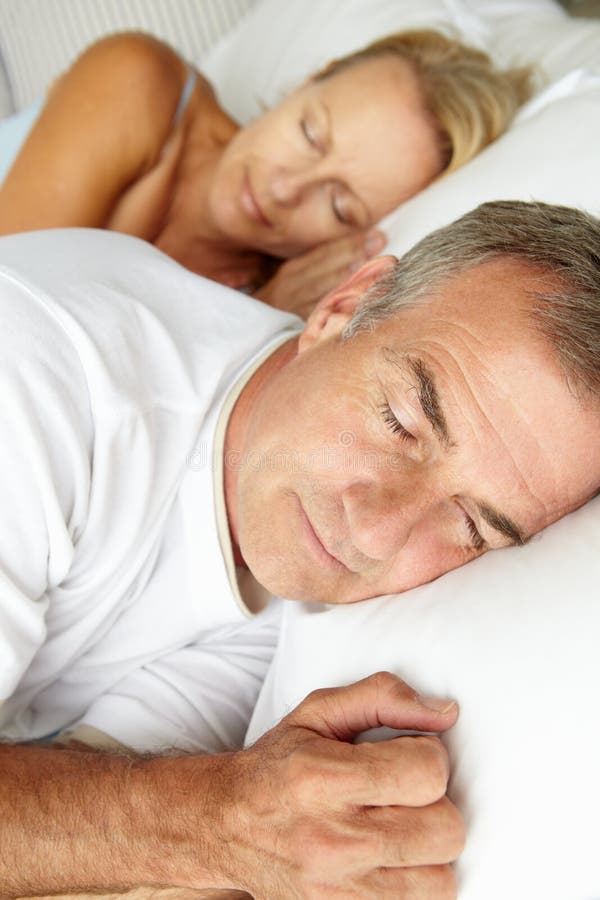 Head and shoulders mid age couple sleeping in bed