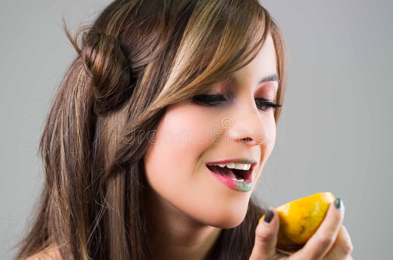 Headshot brunette with dark mystique look and green lipstick holding up an orange, grey background royalty free stock images