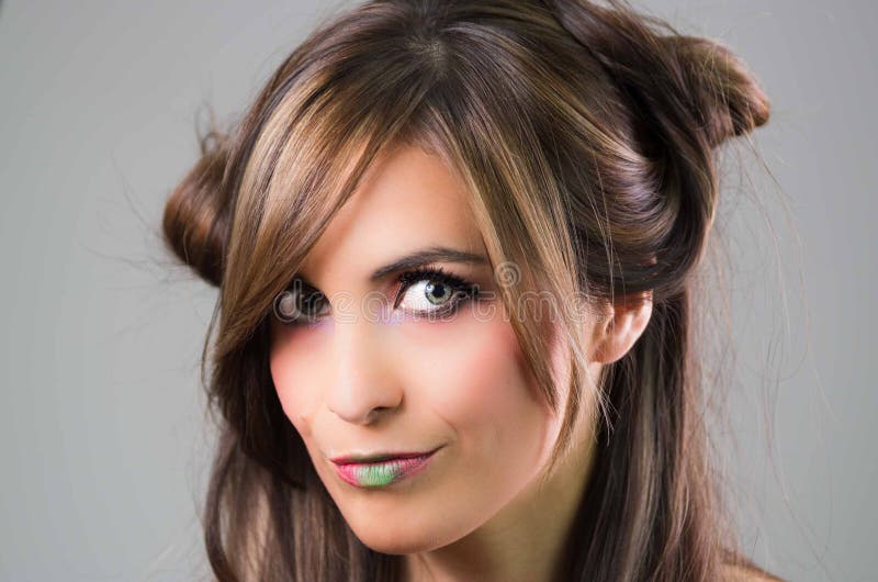 Headshot brunette with dark mystique look and green lipstick posing for camera, grey background royalty free stock image