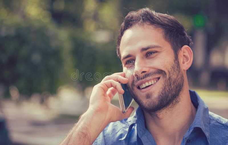 Headshot of a man talking on mobile phone. Casual urban professional using smartphone smiling happy standing outside on a street . Outdoor portrait of modern guy with cellphone. Headshot of a man talking on mobile phone. Casual urban professional using smartphone smiling happy standing outside on a street . Outdoor portrait of modern guy with cellphone