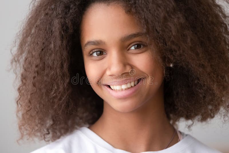 Head shot of african american teen girl looking at camera, black female adolescent teenager with pretty face posing alone, smiling teenage generation z school child with afro hair close up portrait. Head shot of african american teen girl looking at camera, black female adolescent teenager with pretty face posing alone, smiling teenage generation z school child with afro hair close up portrait