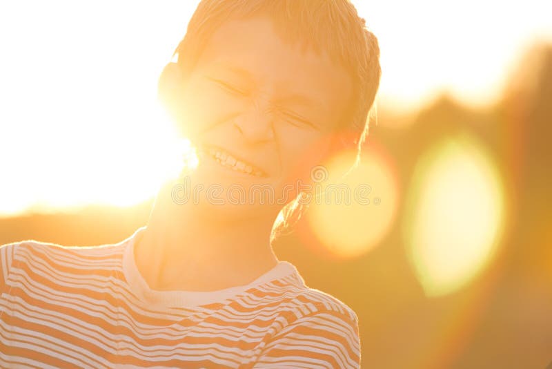 Headshot portrait of screwing up eyes laughing teenage boy in warm sunset backlit with lens flares stock photos Headshot portrait of screwing up eyes laughing teenage boy in warm sunset backlit with lens flares stock photos
