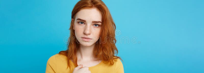 Headshot Portrait of tender redhead teenage girl with serious expression looking at camera. Caucasian woman model with