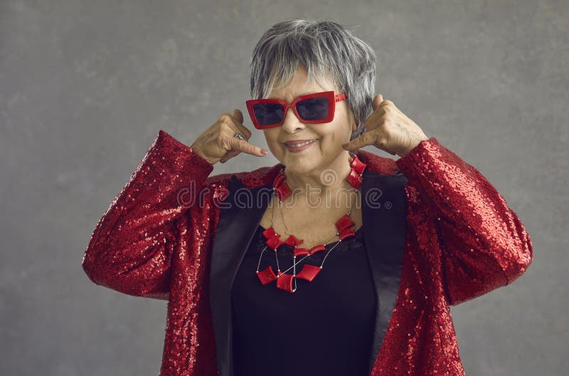 Headshot studio portrait of trendy fashion old woman showing call me gesture