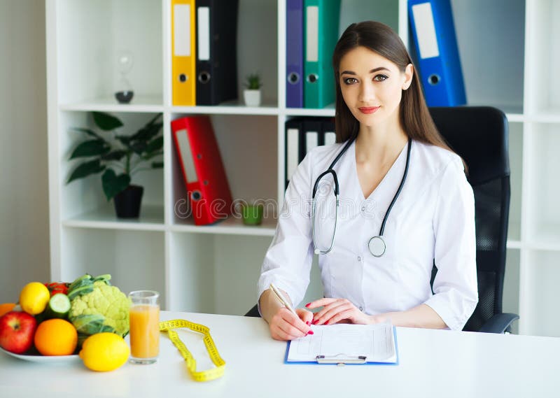 Health and Beauty. The Doctor Signs out a Diet Plan. The Nutritionist Holds in the Hands Fresh Fruits and Vegetables