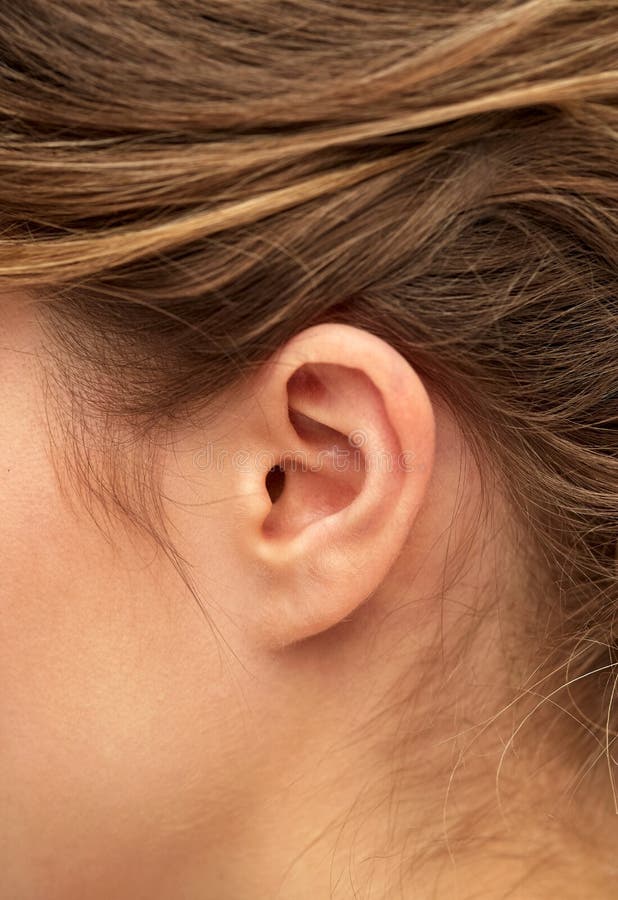 Close up of young woman pointing finger to her ear. 