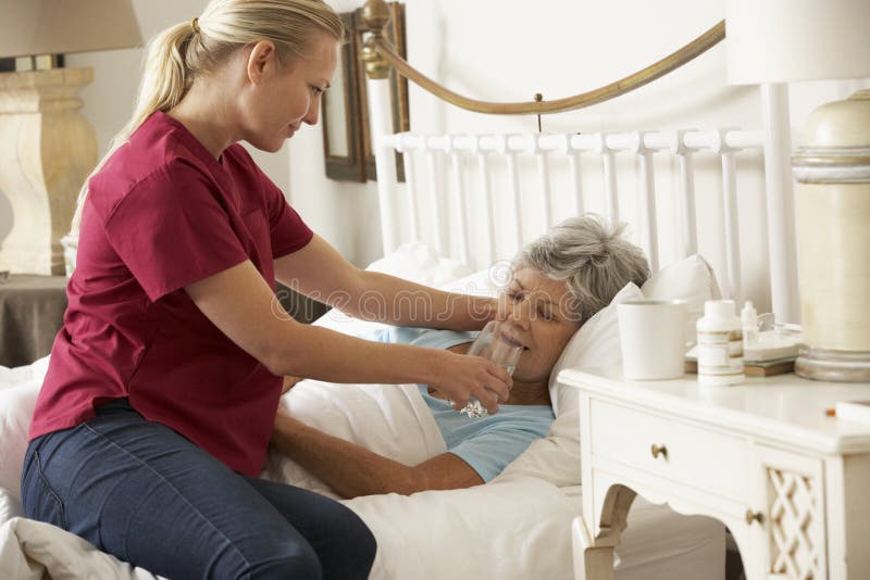 Health Visitor Giving Senior Woman Glass Of Water In Bed At Home stock image Health Visitor Giving Senior Woman Glass Of Water In Bed At Home stock image