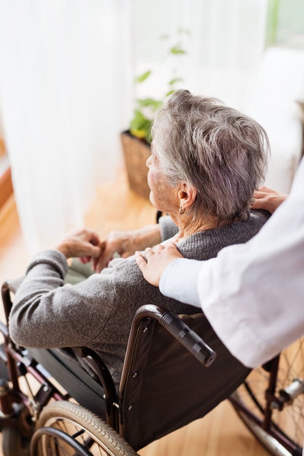 Health visitor and a senior women during home visit. Unrecognizable nurse giving women shoulder massage. Health visitor and a senior women during home visit. Unrecognizable nurse giving women shoulder massage.