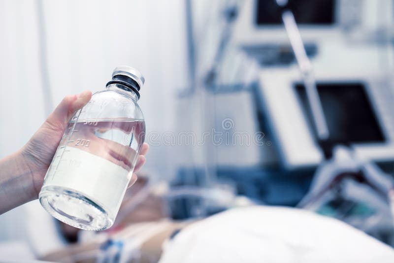 Health worker holds the solution bottle against the patient on the ventilator in the ICU royalty free stock image