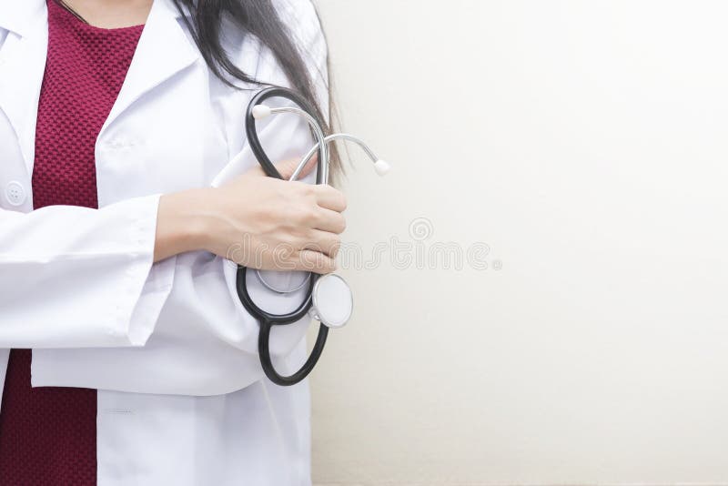 Healthcare background concept. Closeup doctor holding stethoscope standing on white wall with empty space. stock photo Healthcare background concept. Closeup doctor holding stethoscope standing on white wall with empty space. stock photo
