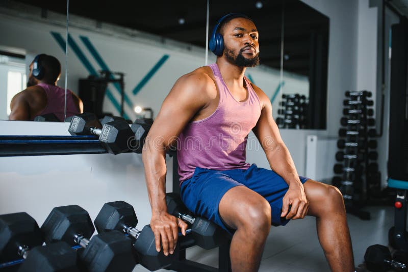 Healthy African Man Working Out with Dumbbells in Gym. Stock Photo