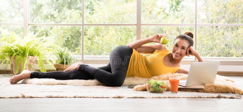 Healthy Asian woman lying on the floor eating salad and looking at camera royalty free stock images Healthy Asian woman lying on the floor eating salad and looking at camera royalty free stock images