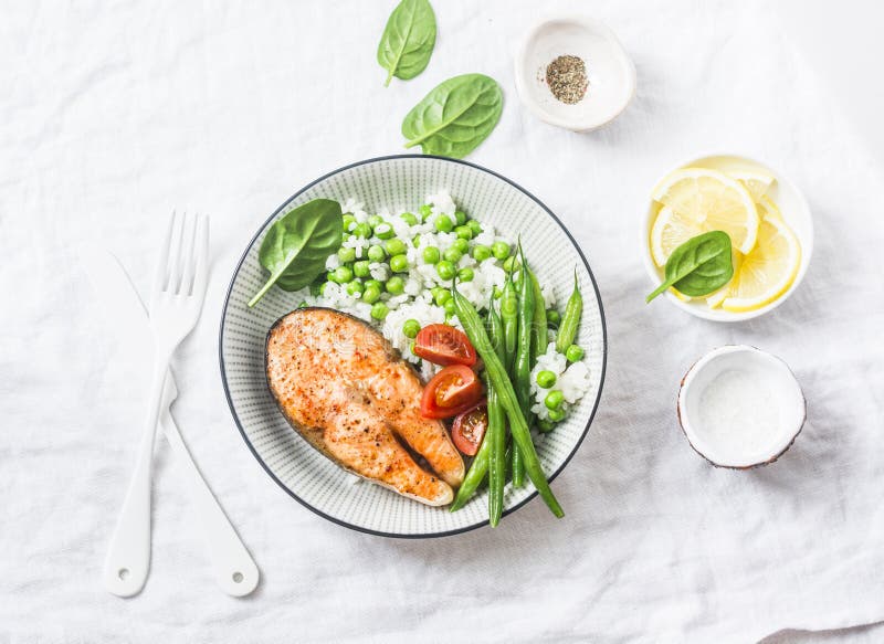 Healthy balanced meal lunch plate - baked salmon with rice and vegetables on a light background